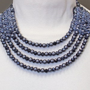 Multi strand gray pearl statement necklace with round gray pearls and gray black diamond color glass beads mixed with rows of gray fabric.