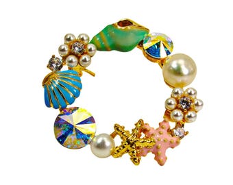 Ozean Thema Pin Brosche mit Muscheln, Seesterne, Perlen und Kristallen, und in den Farben blau, türkis, rosa und weiß.