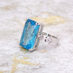 Large blue cubic zirconia statement ring with clear cubic zirconia stones on the sides.
