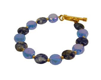 Blue bracelet with blue sodalite stone and blue glass beads in round flat shapes and small gold accents, toggle closure.