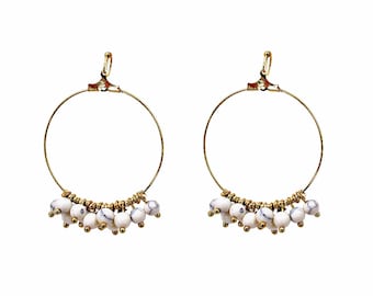 Orecchino a cerchio in filo dorato con piccole perline bianche pendenti.