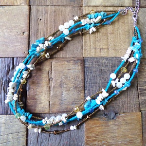 Multi strand beaded necklace in turquoise, brown, and white colors.  Designed with stones, faux pearls, glass beads, and seed beads.