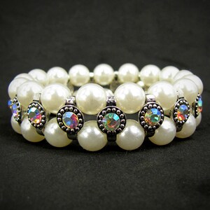 Puede incluir: Un brazalete de doble fila de perlas con detalles plateados y pedrería iridiscente.