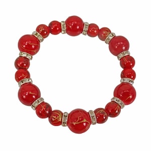 Red glass beaded stretch bracelet with gold splashes of color on each bead and mixed with crystal spacer beads. Women&#39;s red glass bracelet.