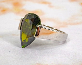 Grande anello con pietra cubica di zirconia a goccia verde, creato con una pietra CZ a taglio sfaccettato incastonata su due lati. Misura 7