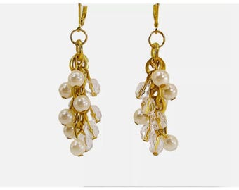 Orecchini con perle bianche e perline trasparenti realizzati con un gruppo di piccole perle rotonde pendenti collegate tra loro.