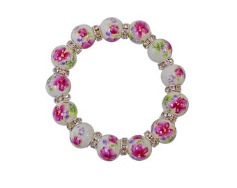 Pode incluir: Pulseira de cerâmica branca com desenhos florais rosa e roxo e detalhes prateados.