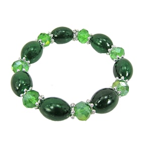 Bracelet extensible en perles de verre vertes avec espaceurs en métal argenté. Il est conçu avec des perles de verre vert foncé et vert clair.