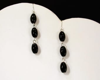 Pendientes de cuentas de vidrio negro hechos con tres cuentas de vidrio en forma de tubo ovalado unidas a mano. 2" de largo.