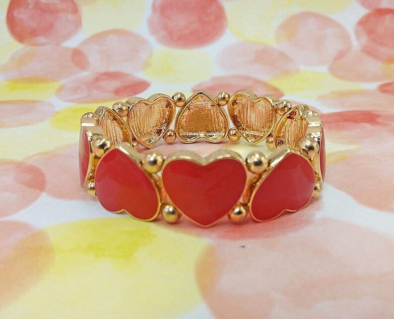 Bracelet extensible en forme de coeur en émail rouge créé avec des perles et des garnitures en émail rouge et dorés. Les breloques cœurs rouges font tout le tour du bracelet. image 2