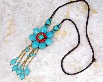 Large turquoise stone beaded flower necklace with a stone tassel.and attached to a brown fabric braided necklace