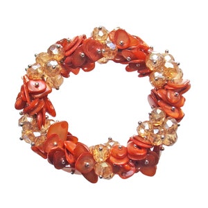 Dark orange shell and light orange glass beaded stretch bracelet, designed with clusters of shell and orange glass beads.