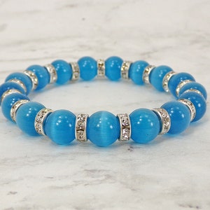 May include: A blue and silver beaded bracelet with clear rhinestones. The bracelet is made of round beads with a smooth, polished finish.