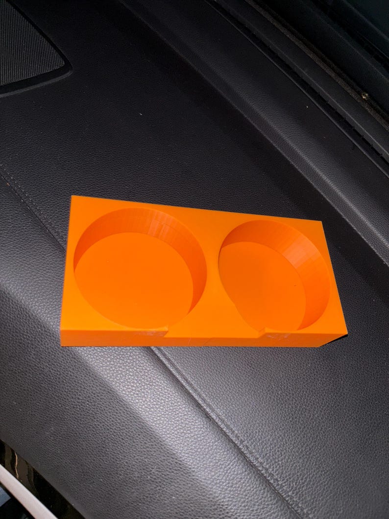 Puede incluir: Portavasos de coche de pl&aacute;stico naranja brillante con dos aberturas circulares. El soporte rectangular tiene una base plana y est&aacute; dise&ntilde;ado para sostener dos tazas o botellas. El portavasos est&aacute; hecho de un material s&oacute;lido y duradero.