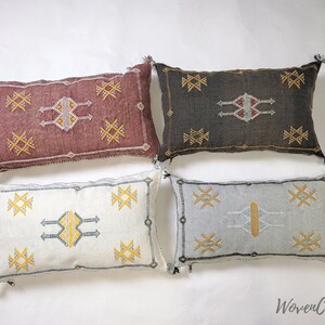 May include: Four decorative throw pillows with geometric patterns in shades of red, brown, white, and blue. The pillows have a woven texture and feature tassels.