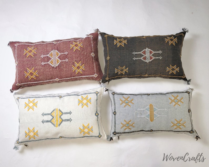 May include: Four decorative throw pillows with geometric patterns in shades of red, brown, white, and blue. The pillows have a woven texture and feature tassels.