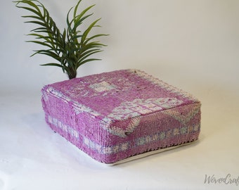 May include: A square pink and white patterned floor cushion with a white border. The cushion is made from woven fabric and has a tufted texture.
