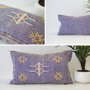 May include: Three purple and white embroidered throw pillows with geometric patterns. The pillows have a light blue background with gold accents.