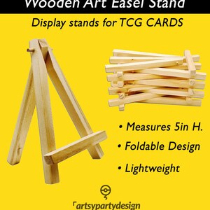 May include: Wooden easel stand for displaying trading cards. The stand is 5 inches tall, foldable, and lightweight. It is made of natural wood and has a simple design.