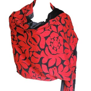 May include: A red and black shawl with a floral pattern and fringe. The shawl is made of a soft, luxurious fabric and is perfect for adding a touch of elegance to any outfit.