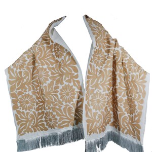 May include: A white shawl with a brown floral pattern and fringe. The pattern features stylized flowers and birds.