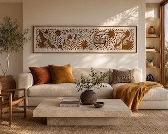 May include: A long, rectangular wall art piece featuring a brown embroidered design of birds, deer, and floral patterns on a cream-colored fabric background, enclosed in a thin wooden frame and displayed horizontally above a beige sofa.
