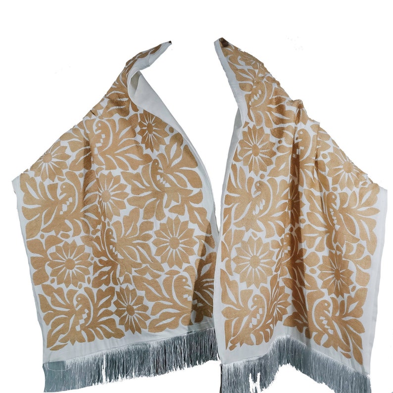 May include: A white shawl with a brown floral pattern and fringe. The pattern features stylized flowers and birds.