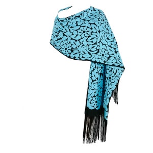 May include: A blue and black shawl with a floral pattern and black fringe.