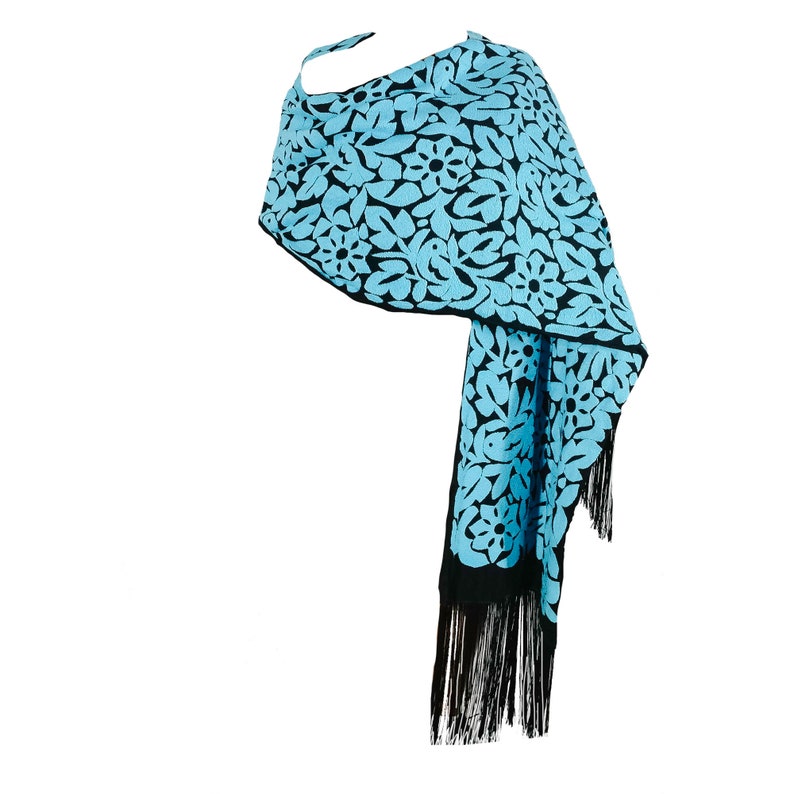 May include: A blue and black shawl with a floral pattern and black fringe.