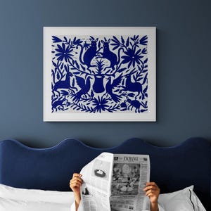 May include: A square framed wall art piece featuring a dark blue intricate folk-art style pattern on a white background. The design displays symmetrical illustrations of rabbits, birds, and floral motifs arranged around a central vessel shape.