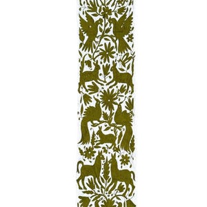Puede incluir: Un camino de mesa rectangular largo de color blanco con un intrincado bordado en verde oliva. El diseño muestra un patrón repetitivo de animales estilizados, incluyendo ciervos, conejos y aves, intercalados con elementos florales y botánicos.