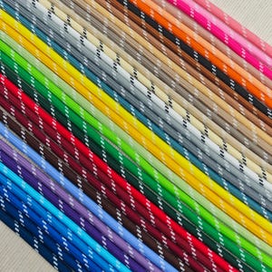 Puede incluir: Una colección de cuerdas coloridas, cada una con un patrón de rayas blancas y negras. Las cuerdas están dispuestas en diagonal, mostrando una variedad de tonos que incluyen azul, verde, rojo, amarillo y rosa. Las cuerdas parecen estar hechas de un material duradero.