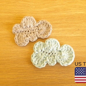 May include: Two crocheted cloud shapes, one in beige and one in light blue, on a wood background. US Terms.