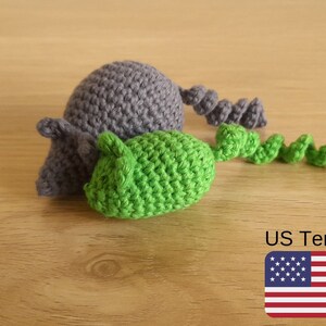 May include: Two crocheted toy mice. One is gray, the other is bright green. Both have curly tails. The toys are handmade and likely intended for pets. The image is a close-up, showing the texture of the yarn and the details of the stitching.