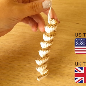 Puede incluir: Adorno de espiral blanco tejido a crochet con detalles de purpurina dorada. Se muestran los términos estadounidenses y británicos con las banderas estadounidense y británica.