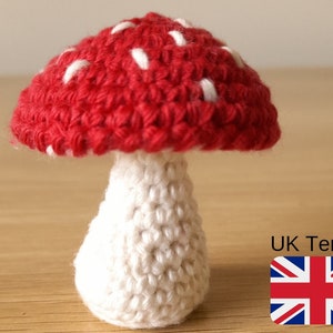 May include: A crocheted mushroom with a red cap and white spots, and a white stem.