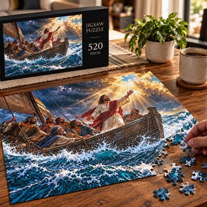 Puede incluir: Un rompecabezas de 520 piezas que muestra una escena de una figura con túnica blanca y faja roja de pie en un bote de madera sobre olas oceánicas oscuras y turbulentas. La caja muestra el texto JIGSAW PUZZLE 520 PIECES.