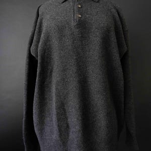 Può includere: Una tazza di ceramica bianca con manico nero e la scritta "But First, Coffee" in grassetto nero. La tazza è posta su uno sfondo sfocato, che suggerisce un'atmosfera accogliente.