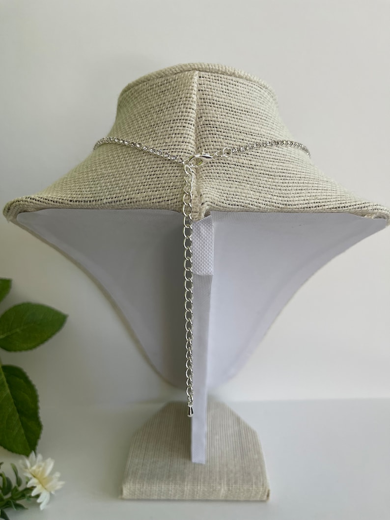 Pu&ograve; includere: Una collana a catena d'argento con chiusura a moschettone. La collana &egrave; esposta su un manichino rivestito in tessuto.
