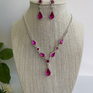 Pu&ograve; includere: Un set di collana e orecchini in argento con strass rosa a forma di goccia. La collana ha un design a forma di Y con strass pi&ugrave; piccoli lungo la catena.