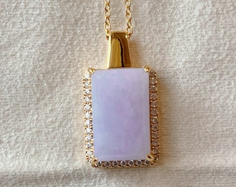 May include: A gold chain necklace with a lavender jade pendant. The pendant is rectangular and has a diamond-like border.