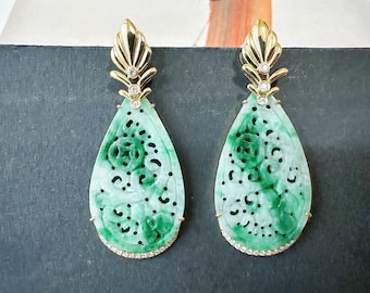 May include: A pair of jade earrings with a gold setting. The earrings feature a teardrop shape with intricate carved designs and are accented with small diamonds. The top of the earrings have a gold leaf design.