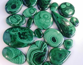 May include: A collection of 15 polished malachite stones in various shapes and sizes. The stones are a deep green color with intricate patterns of swirling veins.