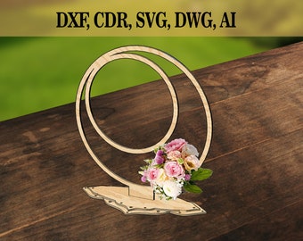 May include: Wooden double ring stand with a floral bouquet. The stand is made of light brown wood and has a decorative base. The rings are stacked on top of each other and are slightly offset. The bouquet is made of pink, white, and yellow flowers.