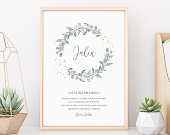 May include: A printable wall art design with a watercolor wreath of blue and green leaves and gold glitter. The name "Julia" is written in cursive inside the wreath. The text below the wreath reads "Lieblingsmensch Danke dass du immer für mich da bist und an meiner Seite stehst Ich freue mich auf alles was wir noch gemeinsam erleben werden Deine Sarah".