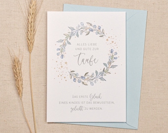 May include: A white card with a blue floral wreath and gold glitter. The text on the card reads "Alles Liebe und Gute zur Taufe. Das erste Glück eines Kindes ist das Bewusstsein, geblückt zu werden."