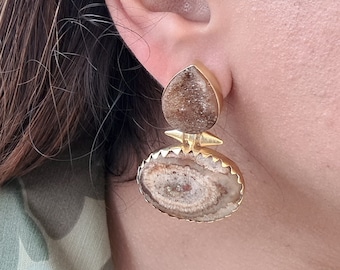 Puede incluir: Un par de pendientes de oro con detalles de piedra de ágata marrón. Los pendientes tienen una piedra en forma de lágrima y una piedra redonda con un patrón circular.
