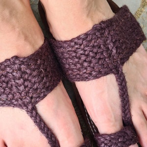 May include: A pair of brown woven sandals with a toe strap. The sandals are made of a thick, rope-like material and have a simple design.
