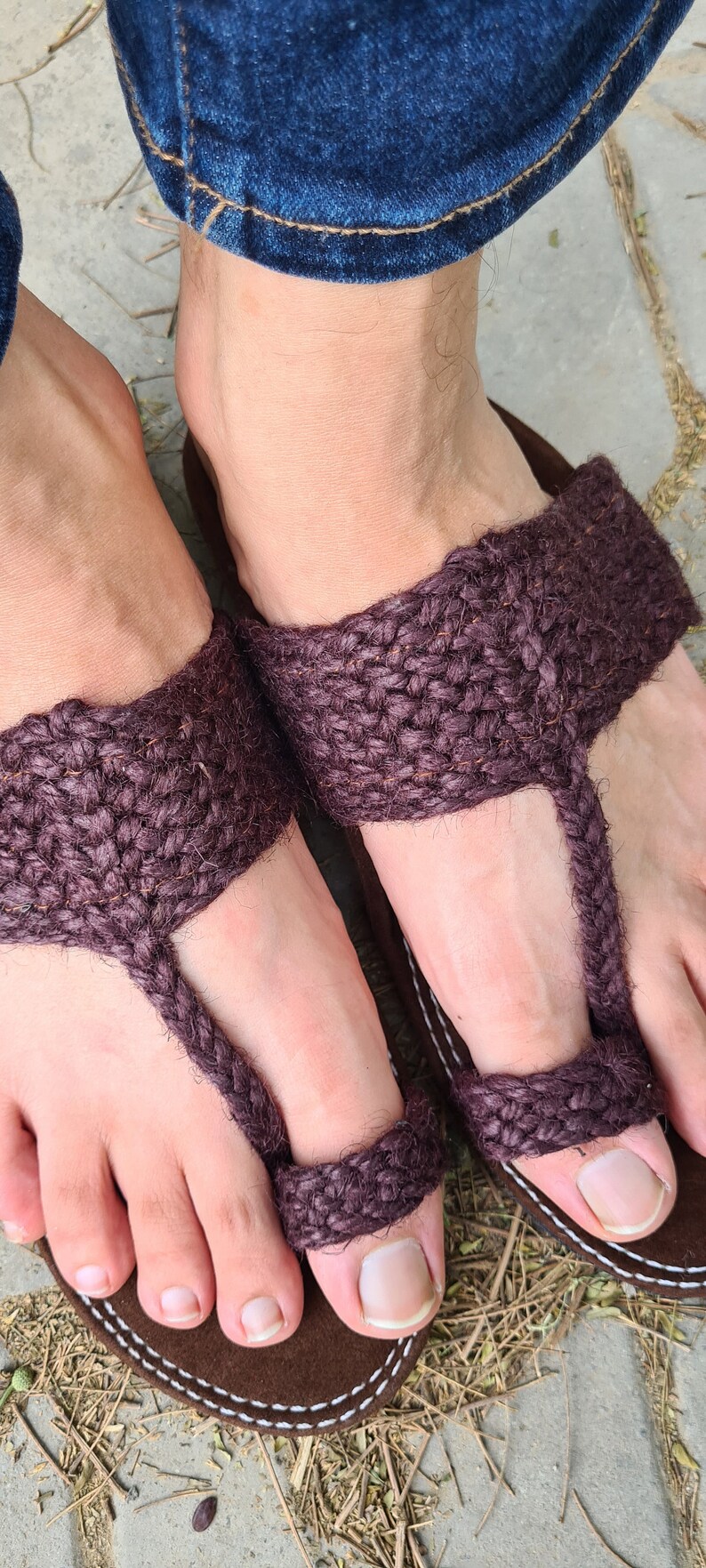 May include: A pair of brown woven sandals with a toe strap. The sandals are made of a thick, rope-like material and have a simple design.