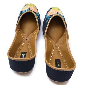 Puede incluir: Un par de zapatos negros bordados sin cordones con dise&ntilde;os florales en tonos rosa, verde y azul. Los zapatos tienen un interior de cuero y una suela cosida. El nombre de la marca est&aacute; impreso en la plantilla.